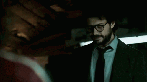 A Man In A Suit And Tie Is Standing In A Dark Room Talking To Another Man . GIF