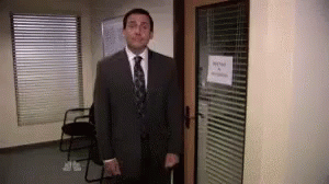 A Man In A Suit And Tie Is Standing In A Doorway Holding A Cane . GIF