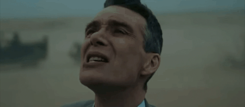 A Man In A Suit And Tie Is Standing In A Field . GIF