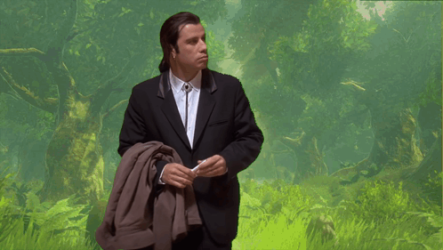 A Man In A Suit And Tie Is Standing In A Field GIF