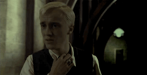 A Man In A Suit And Tie Is Standing In A Hallway . GIF