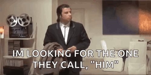 A Man In A Suit And Tie Is Standing In A Living Room And Talking To Someone . GIF