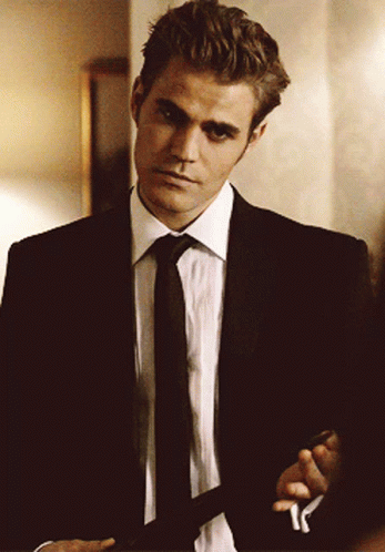 A Man In A Suit And Tie Is Standing In A Room GIF