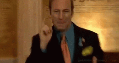 A Man In A Suit And Tie Is Standing In A Room . GIF