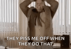 A Man In A Suit And Tie Is Standing In A Room With His Hands On His Head And Screaming . GIF