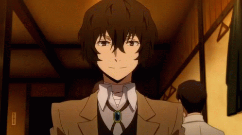 A Man In A Suit And Tie Is Standing In A Room With Other Men . GIF