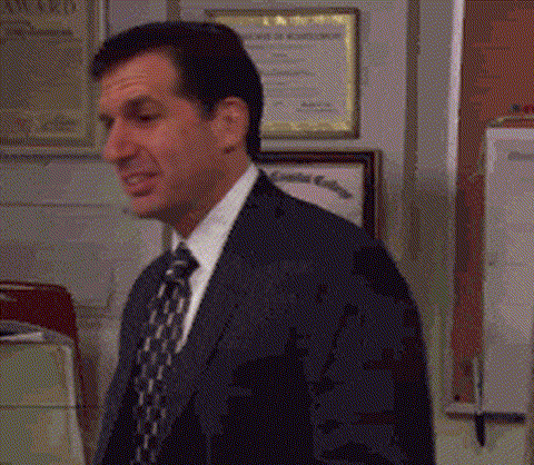 A Man In A Suit And Tie Is Standing In An Office . GIF