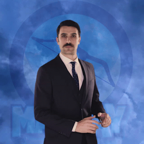 a man in a suit and tie is standing in front of a blue background with the letter m.
