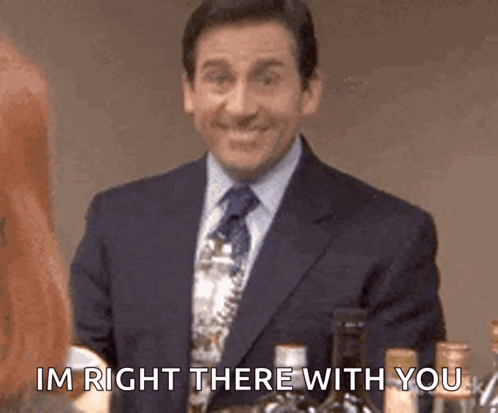 A Man In A Suit And Tie Is Standing In Front Of A Bottle Of Wine And Says `` Im Right There With You '' . GIF