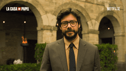 A Man In A Suit And Tie Is Standing In Front Of A Building That Says La Casa De Papel On It GIF
