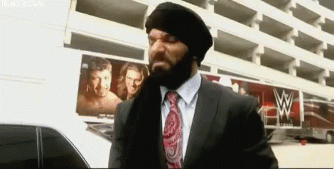 A Man In A Suit And Tie Is Standing In Front Of A Building With A W Logo On It . GIF
