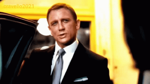 A Man In A Suit And Tie Is Standing In Front Of A Car With The Year 2021 On The Bottom Right GIF