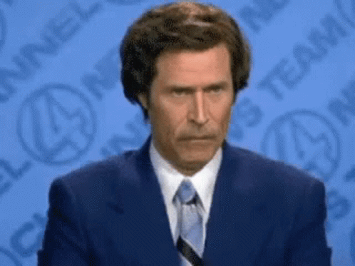 A Man In A Suit And Tie Is Standing In Front Of A Channel 4 Logo GIF