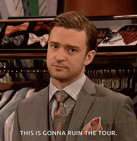 A Man In A Suit And Tie Is Standing In Front Of A Closet Filled With Shirts And Ties . GIF