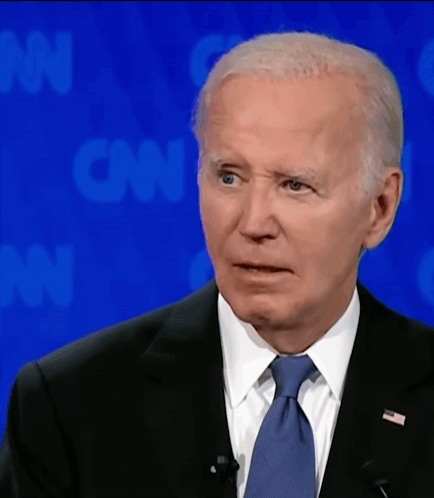A Man In A Suit And Tie Is Standing In Front Of A Cnn Background GIF