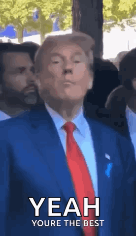 A Man In A Suit And Tie Is Standing In Front Of A Crowd And Making A Funny Face . GIF