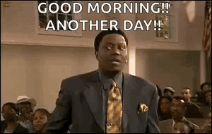 A Man In A Suit And Tie Is Standing In Front Of A Crowd And Saying `` Good Morning ! '' GIF