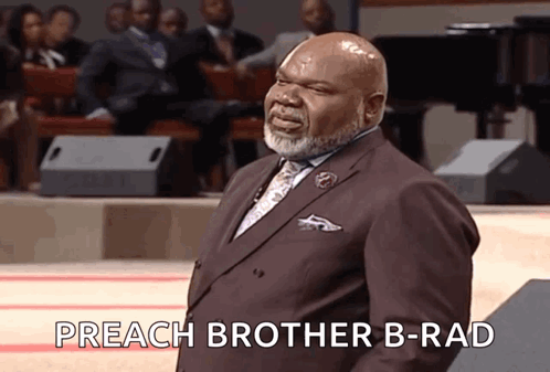 A Man In A Suit And Tie Is Standing In Front Of A Crowd And Saying Preach Brother B-Rad GIF