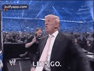 A Man In A Suit And Tie Is Standing In Front Of A Crowd And Screaming . GIF