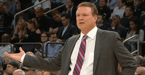 A Man In A Suit And Tie Is Standing In Front Of A Crowd Of People GIF