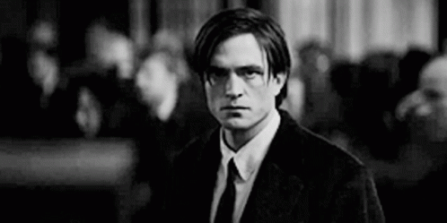 A Man In A Suit And Tie Is Standing In Front Of A Crowd . GIF