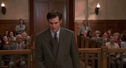 A Man In A Suit And Tie Is Standing In Front Of A Crowd GIF