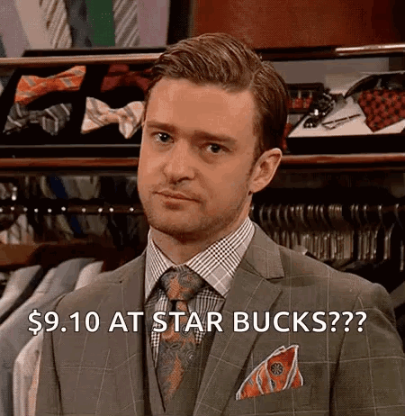 A Man In A Suit And Tie Is Standing In Front Of A Display Of Shirts And Ties . GIF