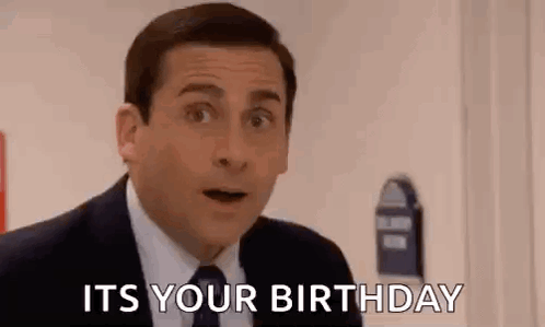 A Man In A Suit And Tie Is Standing In Front Of A Door And Saying `` It 'S Your Birthday '' . GIF