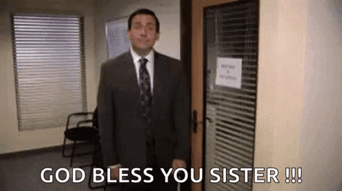 A Man In A Suit And Tie Is Standing In Front Of A Door And Says `` God Bless You Sister '' . GIF