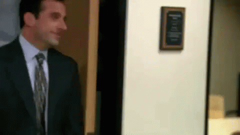 A Man In A Suit And Tie Is Standing In Front Of A Door In An Office . GIF