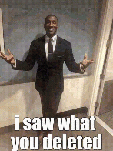 A Man In A Suit And Tie Is Standing In Front Of A Door With The Words I Saw What You Deleted Written On The Bottom GIF