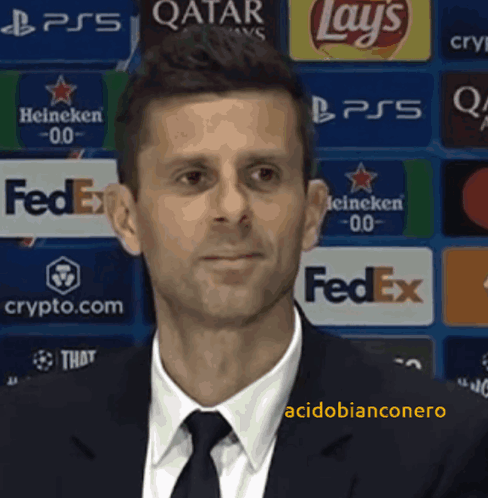A Man In A Suit And Tie Is Standing In Front Of A Fedex Banner GIF