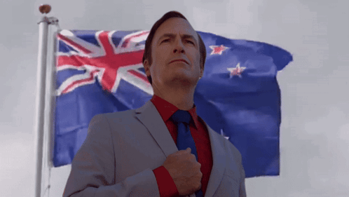 A Man In A Suit And Tie Is Standing In Front Of A Flag GIF