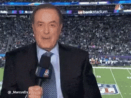 A Man In A Suit And Tie Is Standing In Front Of A Football Field GIF