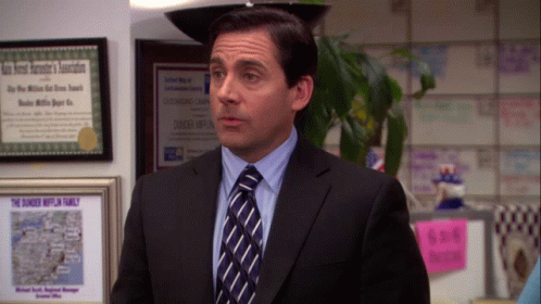 A Man In A Suit And Tie Is Standing In Front Of A Framed Certificate That Says " The Dunkey Hufflin Family " GIF