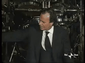 A Man In A Suit And Tie Is Standing In Front Of A Gibraltar Drum GIF