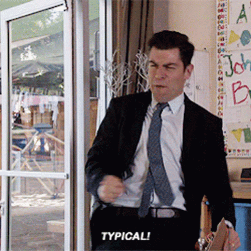 A Man In A Suit And Tie Is Standing In Front Of A Glass Door And Says Typical GIF