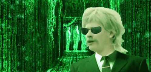 A Man In A Suit And Tie Is Standing In Front Of A Matrix Background GIF