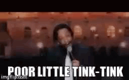 A Man In A Suit And Tie Is Standing In Front Of A Microphone . GIF