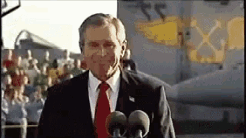 A Man In A Suit And Tie Is Standing In Front Of A Microphone . GIF