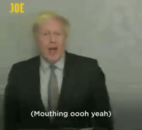 A Man In A Suit And Tie Is Standing In Front Of A Microphone . GIF