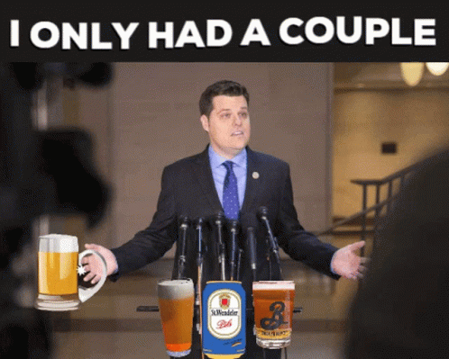 A Man In A Suit And Tie Is Standing In Front Of A Microphone With A Can Of St. Wendel Beer On The Podium GIF