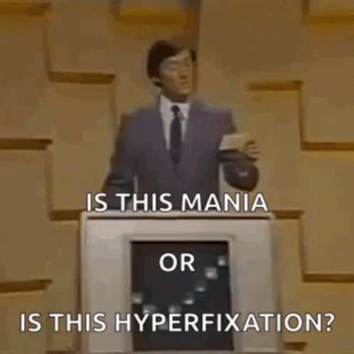 A Man In A Suit And Tie Is Standing In Front Of A Podium And Asking Is This Mania Or Is This Hyperfixation ? GIF