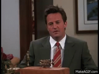 A Man In A Suit And Tie Is Standing In Front Of A Podium In A Room . GIF
