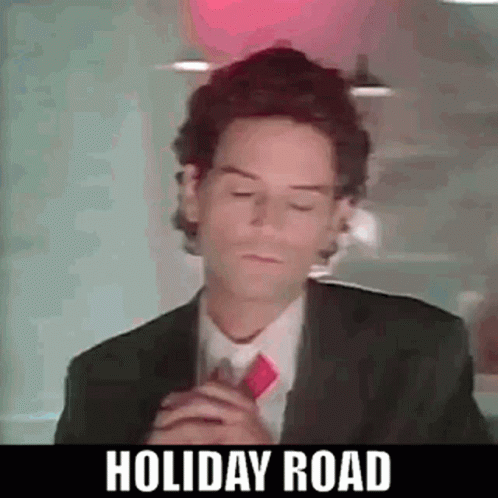 A Man In A Suit And Tie Is Standing In Front Of A Red Light . GIF