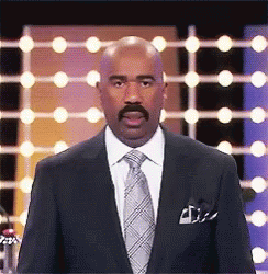 A Man In A Suit And Tie Is Standing In Front Of A Row Of Lights . GIF