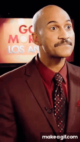 A Man In A Suit And Tie Is Standing In Front Of A Screen That Says Go Monday Los Angeles GIF