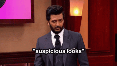A Man In A Suit And Tie Is Standing In Front Of A Screen That Says Suspicious Looks GIF