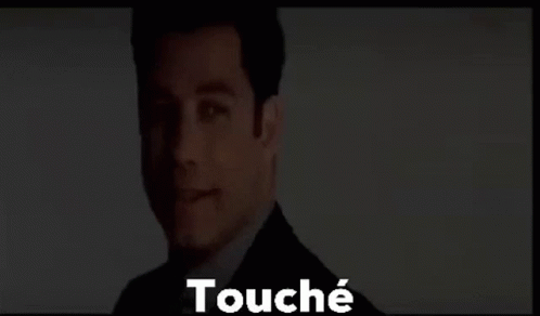 A Man In A Suit And Tie Is Standing In Front Of A Screen With The Words Touché Written On It . GIF