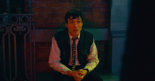 A Man In A Suit And Tie Is Standing In Front Of A Sign That Says ' A ' GIF